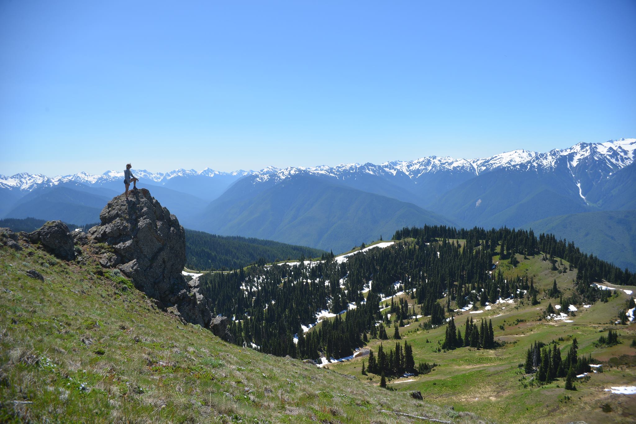 A wide mountain ridge in the Pacific Northwest with Jen standing on a rocky outcrop